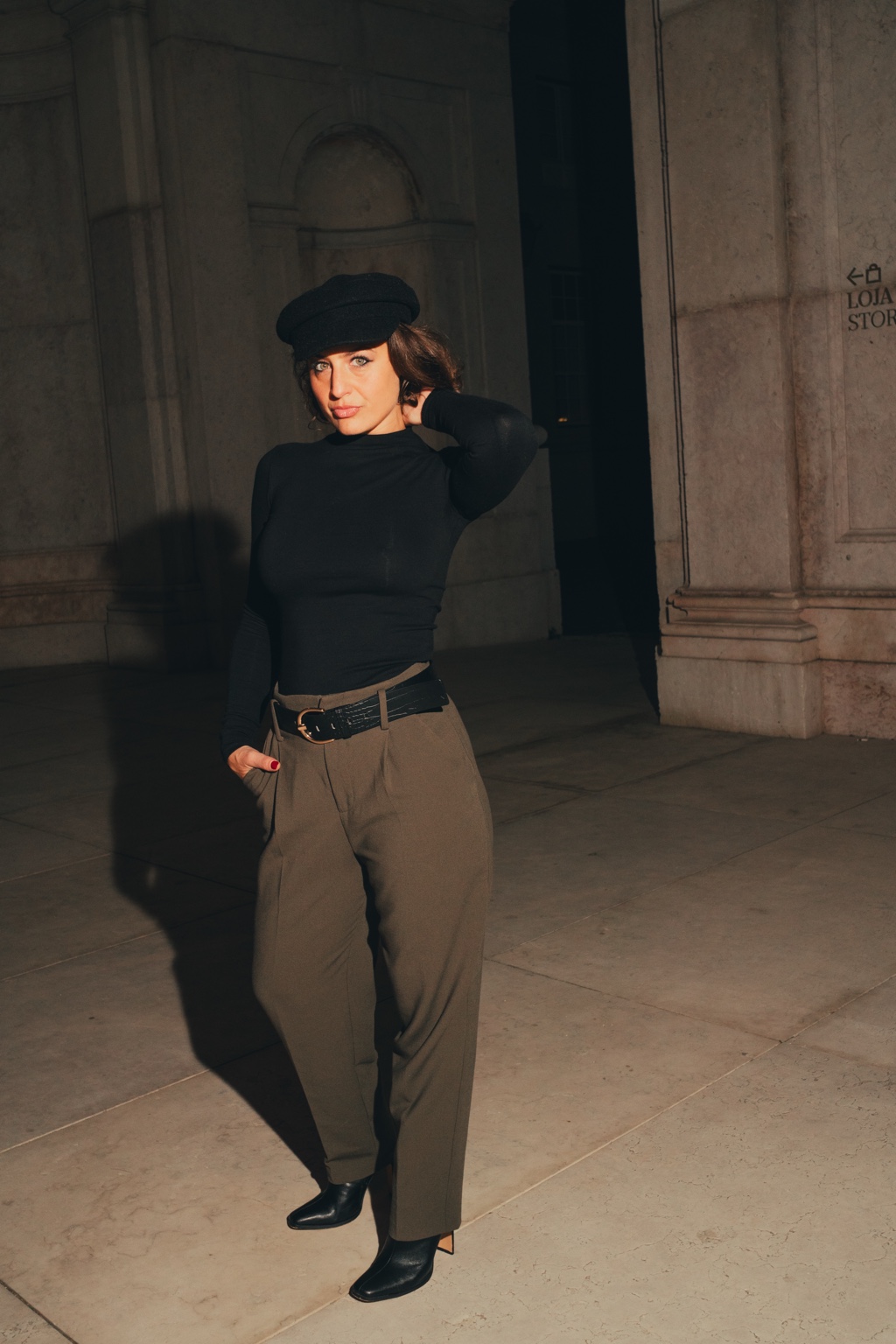 Christina in a black beret, photographed beside stone columns