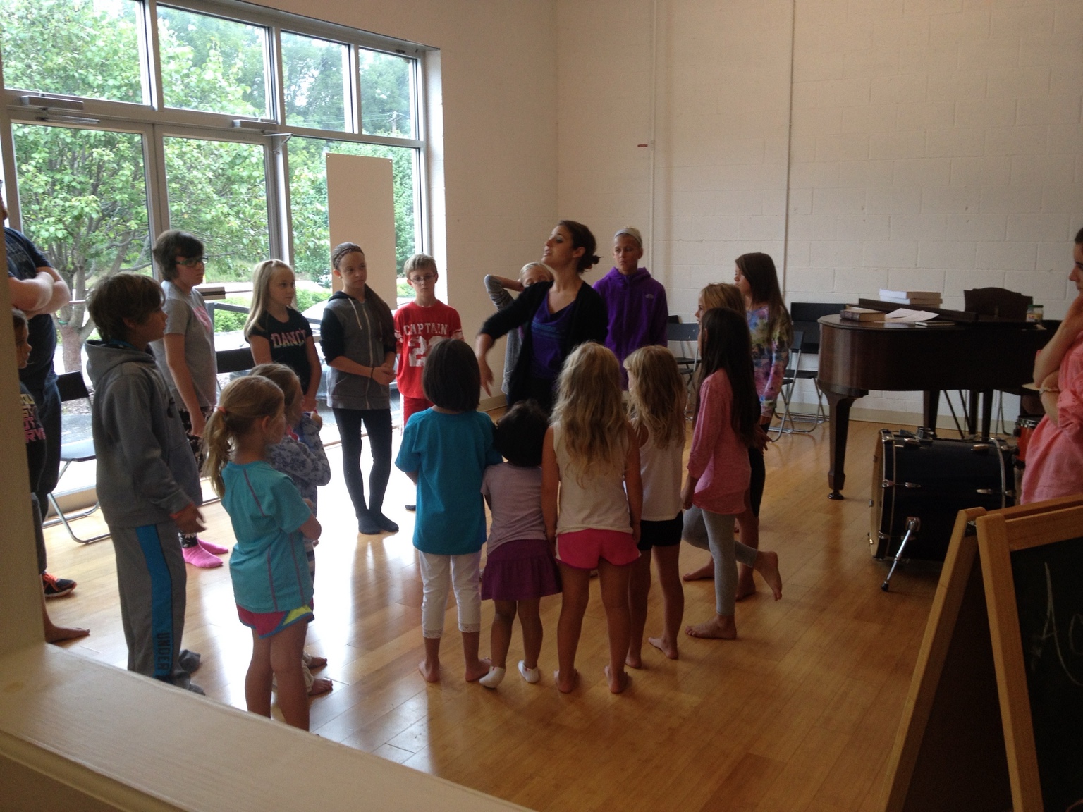 Christina guiding a circle of young performers in a rehearsal room